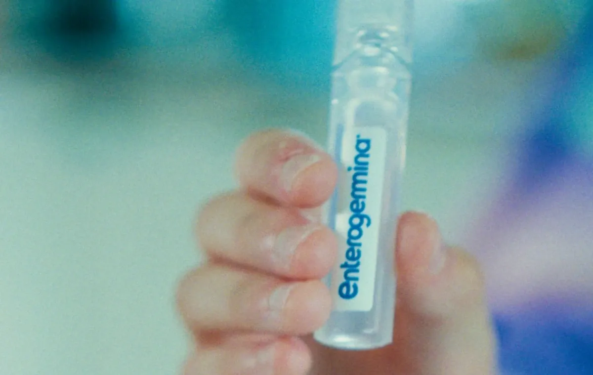 Uma pessoa segurando um pequeno frasco próximo à boca.